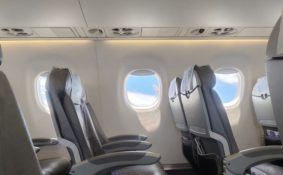 Interior of an empty airplane cabin featuring window view of sky and clouds, perfect for travel theme.